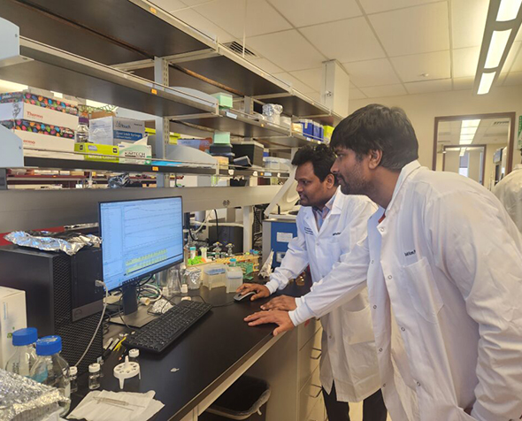 Sunil Kumar and another researcher in white lab coats looking at a screen