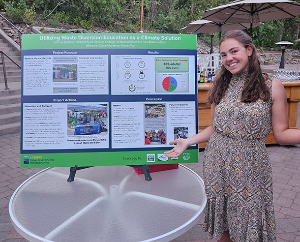 Sidney Barbier stands next to her poster presentation.