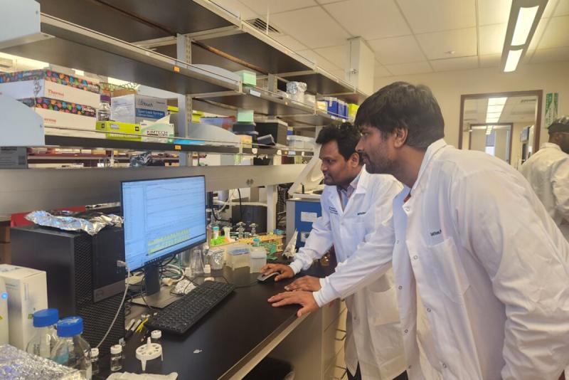 Sunil Kumar and another researcher in white lab coats looking at a screen