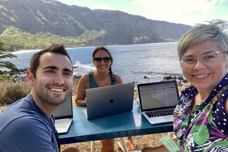 Robin Tinghitella (center) and her fellow researchers work at a table on their computers in Hawaii.
