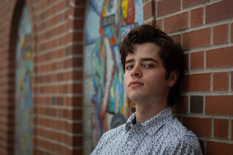 Student standing by brick wall